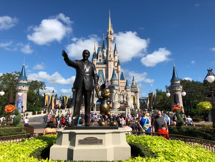 Walt Disney and Mickey Mouse waving in front of the castle in Disneyland