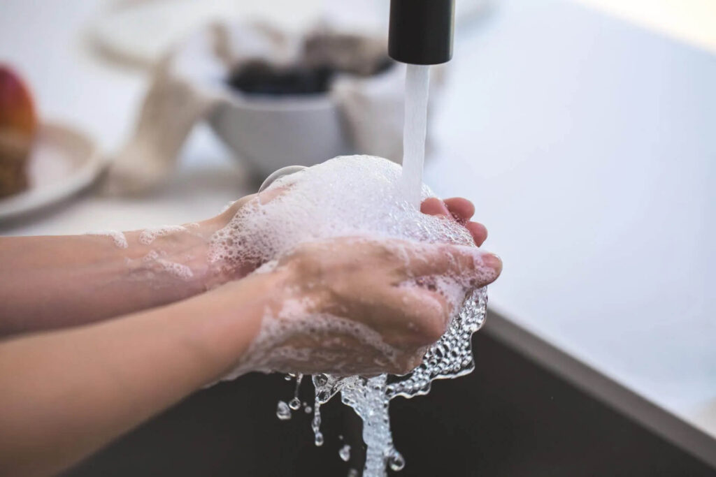 Person washing hands with hot water 