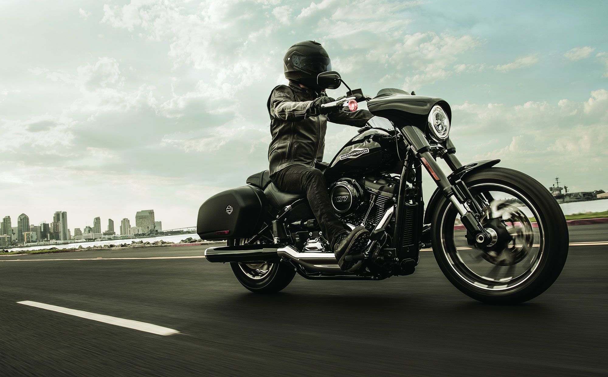 Man riding a Harley Davidson along a coastal road