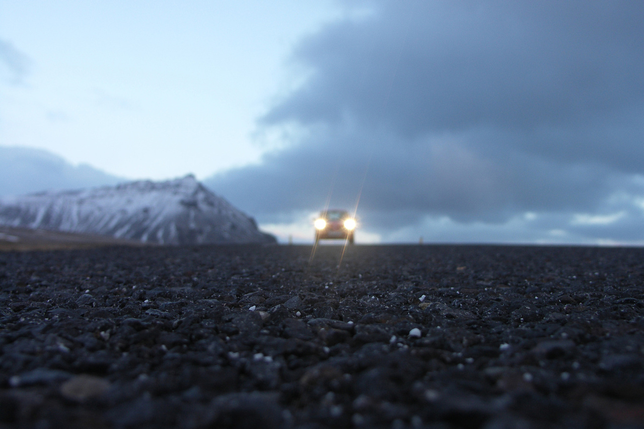 Car with headlights on driving through a storm in an isolated location