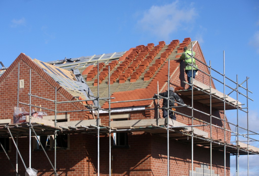 A man on top of a house building the roof